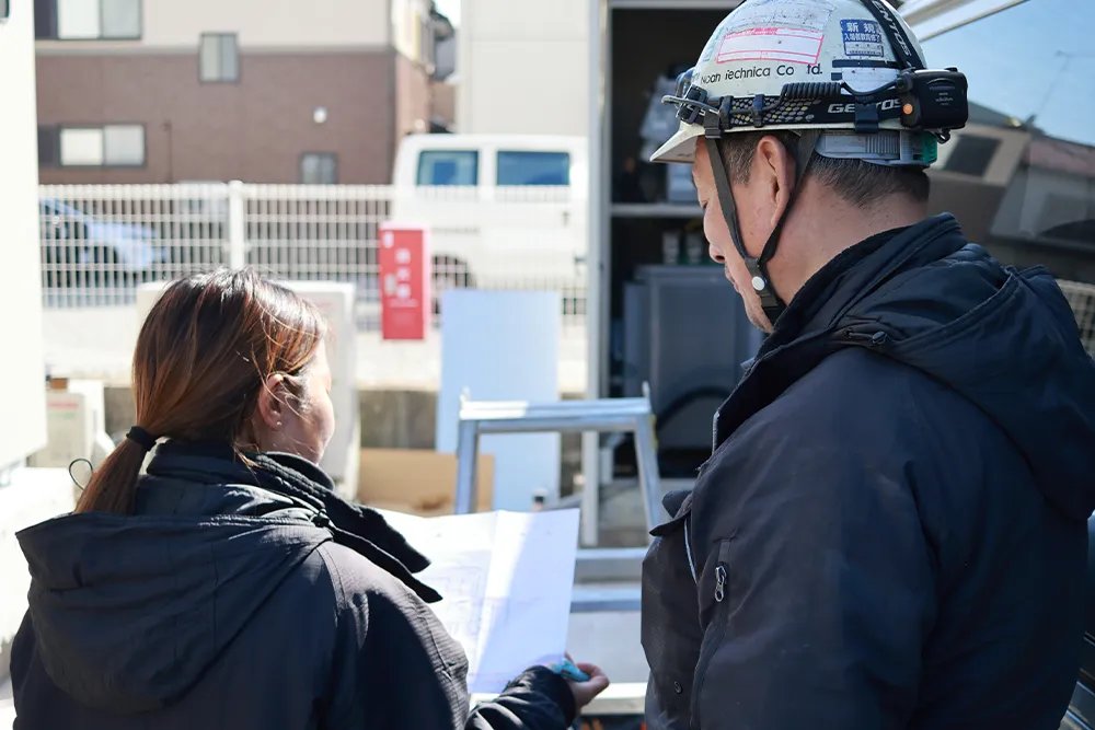 電気工事の図面を確認するスタッフの後ろ姿